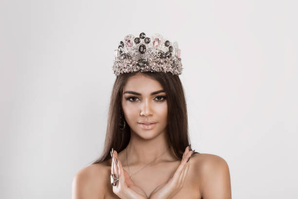 istock Beauty bride with pastel colors makeup silver crown looking at you camera smiling. Beautiful face of young adult woman with clean fresh skin hands around face- isolated on white background studio wall 1204156748
