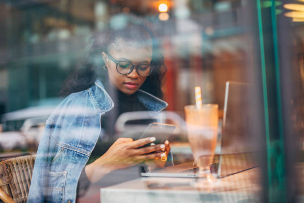 istock Black woman sitting alone in cafe and using mobile phone 1204158689