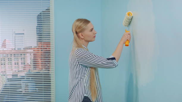 istock Woman builder painting wall 1204159332
