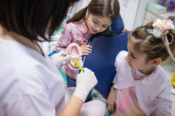 dentist showing young girls how to brush teeth the right way - human teeth defending dental equipment brushing imagens e fotografias de stock