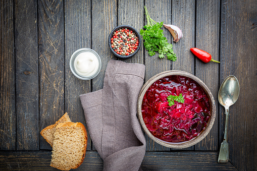 Traditional Ukrainian Russian vegetable beet soup, borscht on wooden background, top view