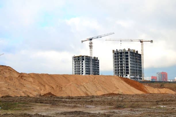 Tower cranes constructing a new residential building at a construction site against blue sky. Renovation program, development, concept of the buildings industry.