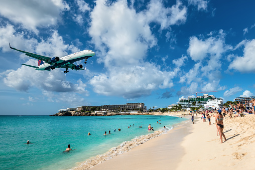 Maho beach, Saint Martin - December 17, 2018: The commercial jet Delta Air Lines approaches Princess Juliana airport above onlooking spectators in Maho beach, Sint Maarten - Saint Martin island.