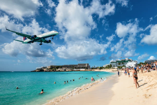 Maho beach in St Martin: one of the main attractions for plane spotters! Maho beach, Saint Martin - December 17, 2018: The commercial jet Delta Air Lines approaches Princess Juliana airport above onlooking spectators in Maho beach, Sint Maarten - Saint Martin island. wow airlines stock pictures, royalty-free photos & images