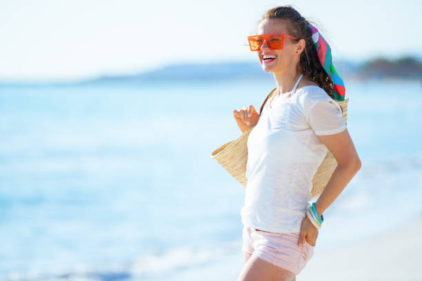 istock smiling trendy woman on seashore looking into distance 1204164292