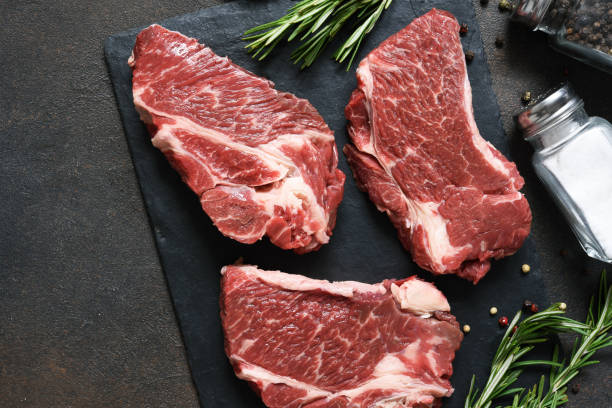 istock Raw marbled beef steak on a stone board. Spices, dishes. Top view flat lay with copy space. 1204165126