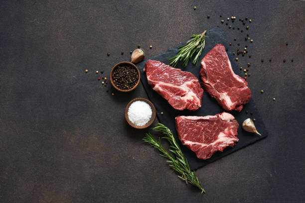 istock Raw marbled beef steak on a stone board. Spices, dishes. Top view flat lay with copy space. 1204165155