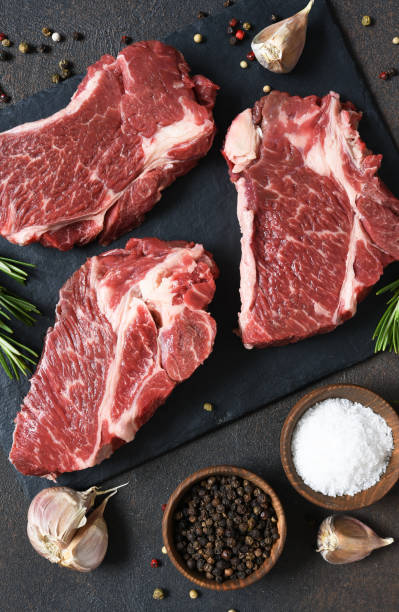 istock Raw marbled beef steak on a stone board. Spices, dishes. Top view flat lay with copy space. 1204165173