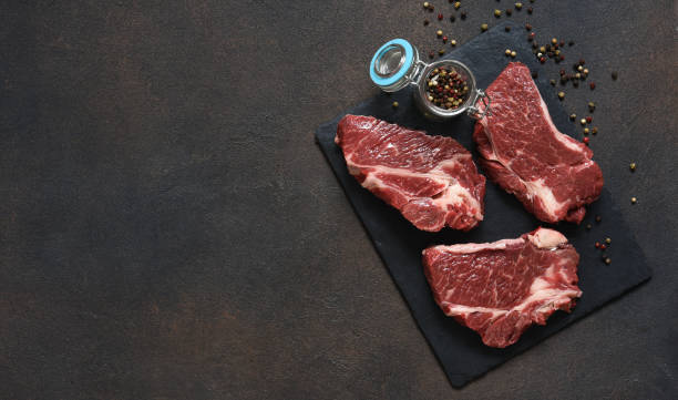 istock Raw marbled beef steak on a stone board. Spices, dishes. Top view flat lay with copy space. 1204165174