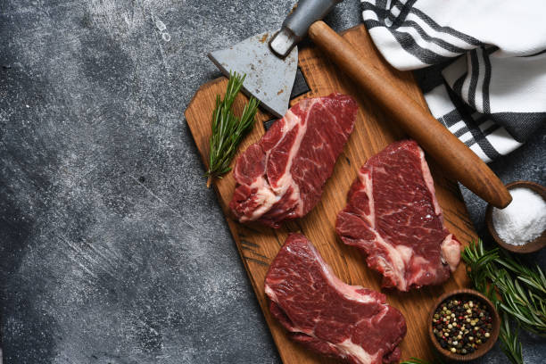 istock Raw beef steak beef steak on a wooden board with an ax. 1204165276