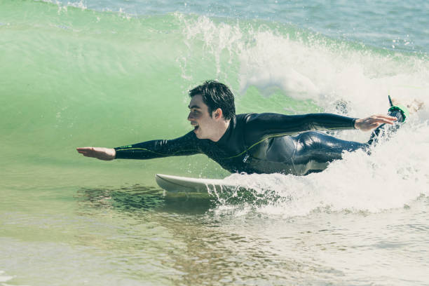 istock Excited young man swimming on surfboard in ocean 1204167725