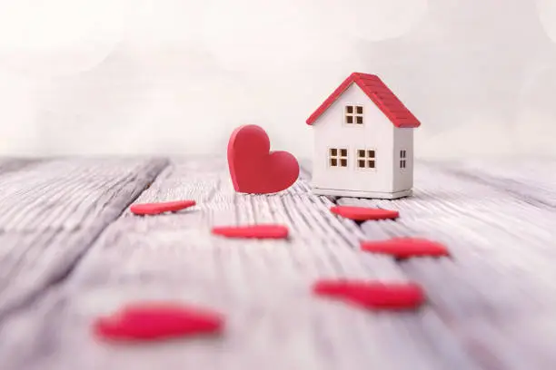 Photo of Toy house and red hearts on light defocused background. Valentines day concept