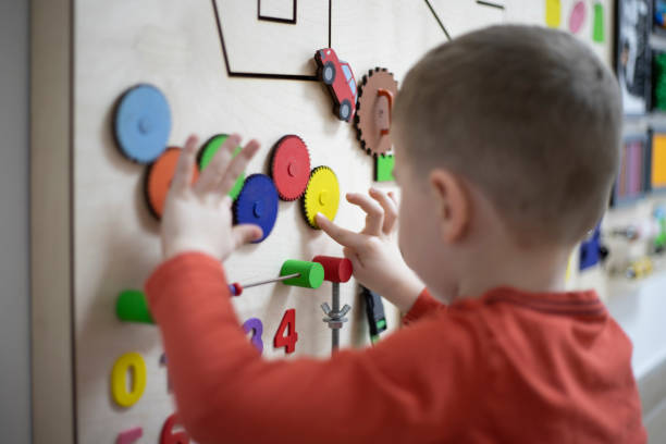 Boy playing with the interactive board Three years old boy playing on the busy board at his psychotherapy session. montessori education photos stock pictures, royalty-free photos & images