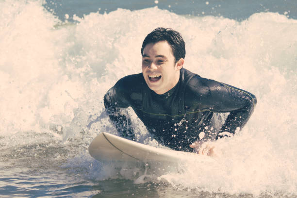 istock Excited young man swimming on surfboard in sea 1204168566