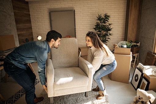 Couple carrying sofa in new apartment