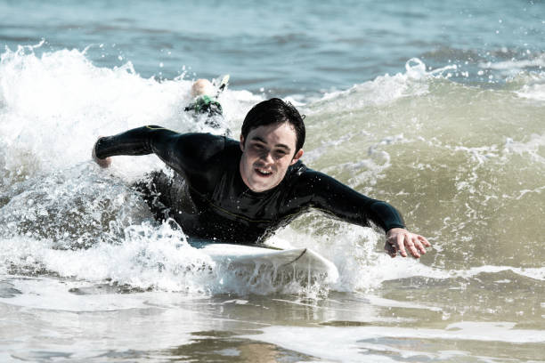 istock Excited handsome man swimming on surfboard in sea 1204168847