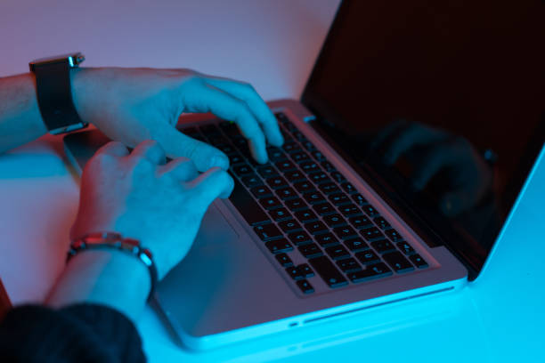 istock Man working night online  laptop in the color light on a table night background 1204169080