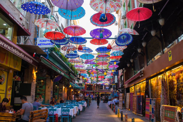 Istanbul, Turkey - September 18th 2019. Colourful umbrellas hang from the sky covering a street of bars, restaurants and shops in the Moda district of Kadikoy on the Asian side of Istanbul