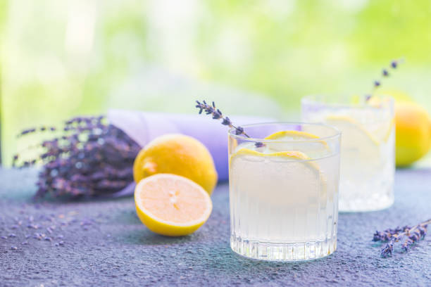 Lemonade with lemons and lavender Lemonade with lemons and lavender on stone table over nature background jug photos stock pictures, royalty-free photos & images