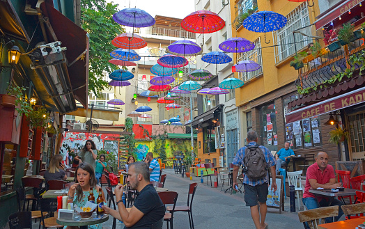 Istanbul, Turkey - September 18th 2019. Colourful umbrellas hang from the sky covering a street of bars and restaurants in the Moda district of Kadikoy on the Asian side of Istanbul