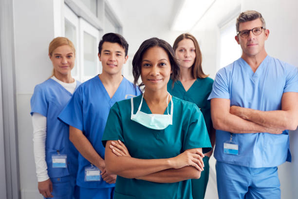 Portrait Of Multi-Cultural Medical Team Standing In Hospital Corridor Portrait Of Multi-Cultural Medical Team Standing In Hospital Corridor scrubs stock pictures, royalty-free photos & images