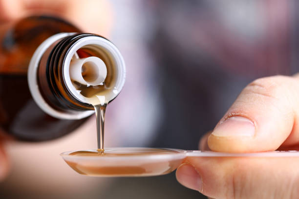 hombre enfermo sosteniendo en las manos vial con jarabe primer plano - cough remedy fotografías e imágenes de stock