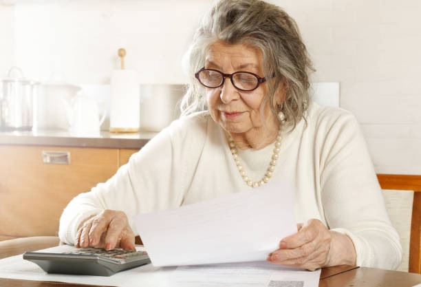 istock An old woman looking through receipts with a calculator 1204183842