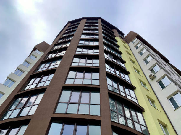 istock Multi-storey building on a background of blue sky. Tall building with mirrored windows, bottom view. 1204183958