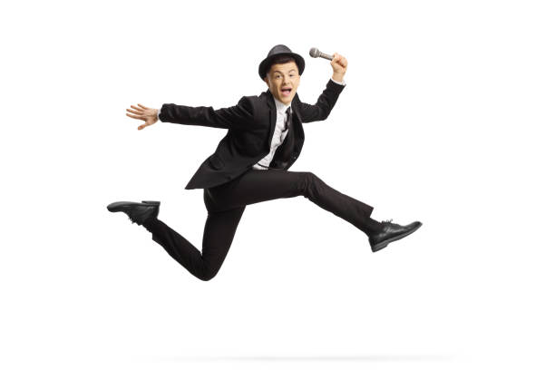 istock Young guy in a suit holding a microphone and jumping 1204188408