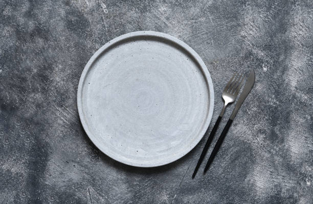 Kitchen table with empty plate and towel. Cooking stone backdrop. Top view with copy space. stock photo