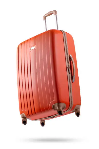 Studio shot of a flying orange suitcase