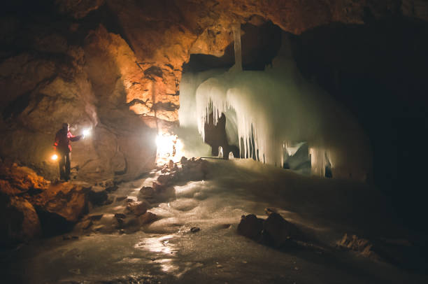 persona iluminando la cueva helada - light guide fotografías e imágenes de stock