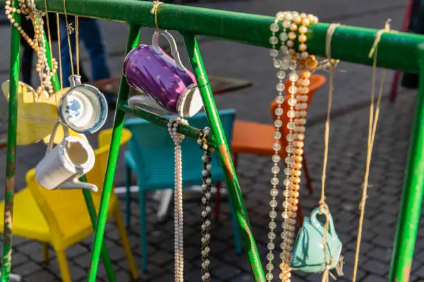 Mugs, neckchains, pearls, cans, cups and colors on a fench in a shoppingstreet