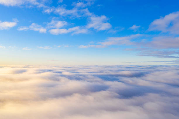 Aerial view White clouds in blue sky. Top view. View from drone. Aerial bird's eye view. Aerial top view cloudscape. Texture of clouds. View from above. Sunrise or sunset over clouds stock photo