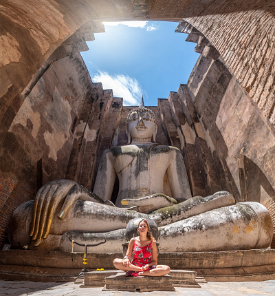 Tourist meditating in front of Phra Ajana buddha statue at Wat Si Chum, Sukhothai, Thailand