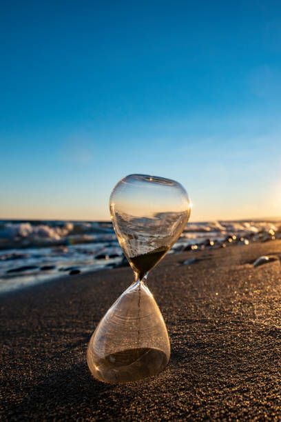istock Time is over. Hourglass on the beach at sunset 1204196572