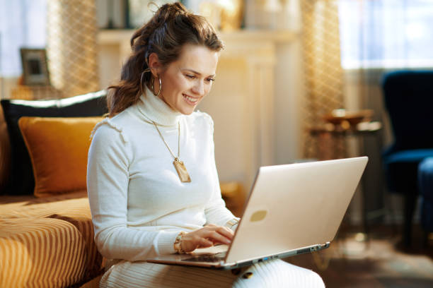glückliche frau mit laptop im modernen zuhause am sonnigen wintertag - autumn women clothing retail stock-fotos und bilder