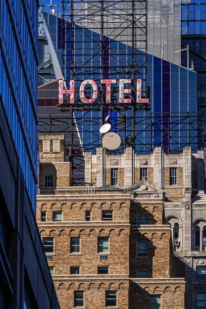 un antiguo letrero de neón en lo alto de un antiguo hotel en la ciudad de nueva york contrasta con los edificios modernos que se han levantado por encima de él - hotel sign built structure building exterior fotografías e imágenes de stock