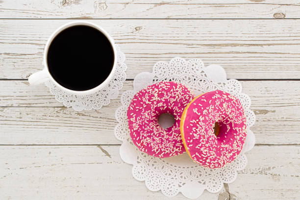 istock Donuts and coffee on a white wood background, top view 1204200629