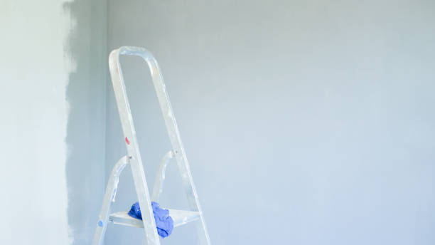 istock foreground stepladder. installation of an office air conditioner. Worker drilling a hole for connecting indoor and outdoor units. Ladder in the foreground. mount split system for air conditioning. elevated wall painting 1204205491