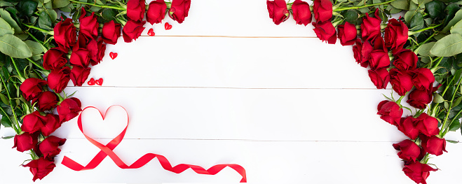 Red roses border on white wooden background with copy space, web banner format
