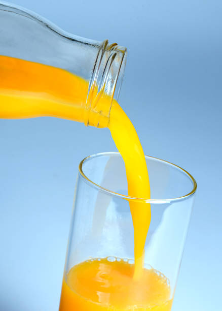 istock Orange juice pouring from a bottle into a glass 1204211687