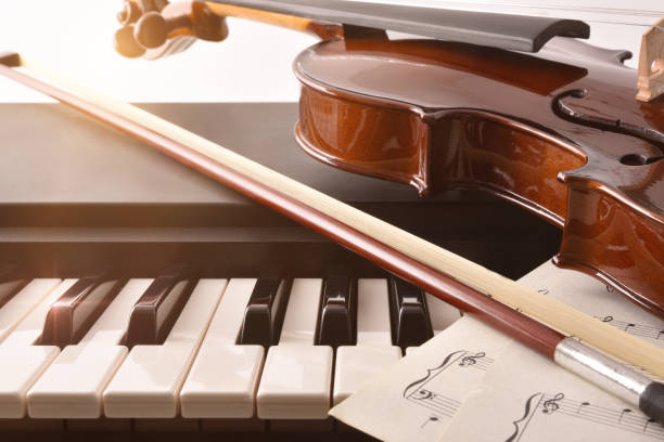 istock Violin and bow detail on piano keys white background front 1204212233