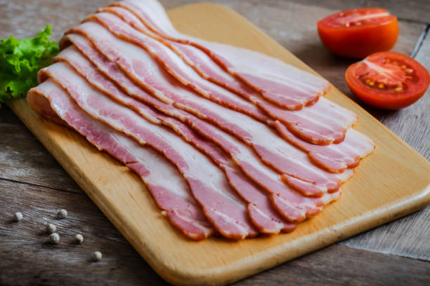 istock Raw sliced bacon on wooden board 1204215429