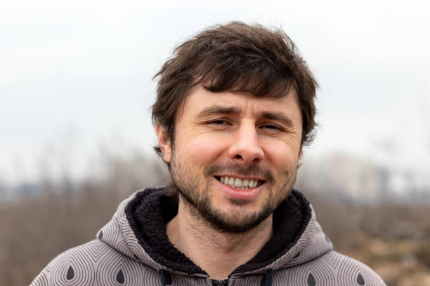 istock A handsome happy smiling bearded man outside against a blurred background. Man in a jacket with a hood 1204219429