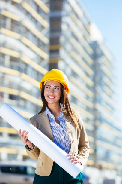 istock Portrait of cheerful engineer with blueprint on construction site 1204221342