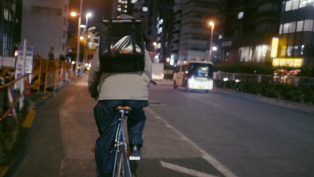 Japanese food courier cycling in the night (slow motion)