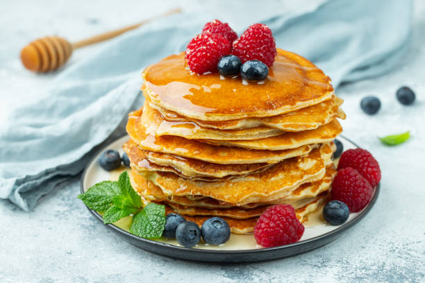 istock Close-up delicious pancakes, with fresh blueberries, raspberry's and honey on a light background 1204222906