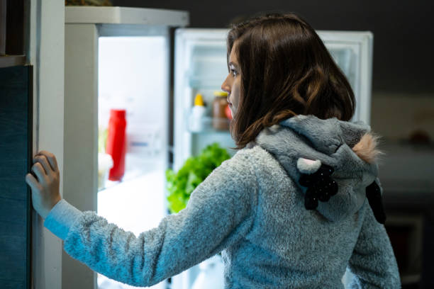 istock Young girl at night in front of a refrigerator 1204226793