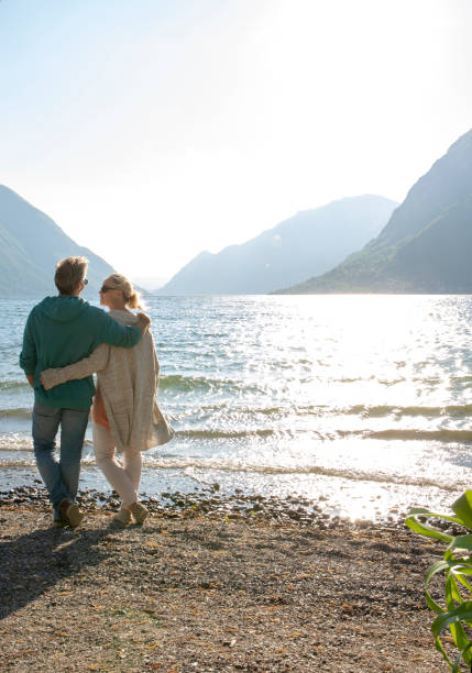 istock Mature couple walk along beach, look out to view 1204229629